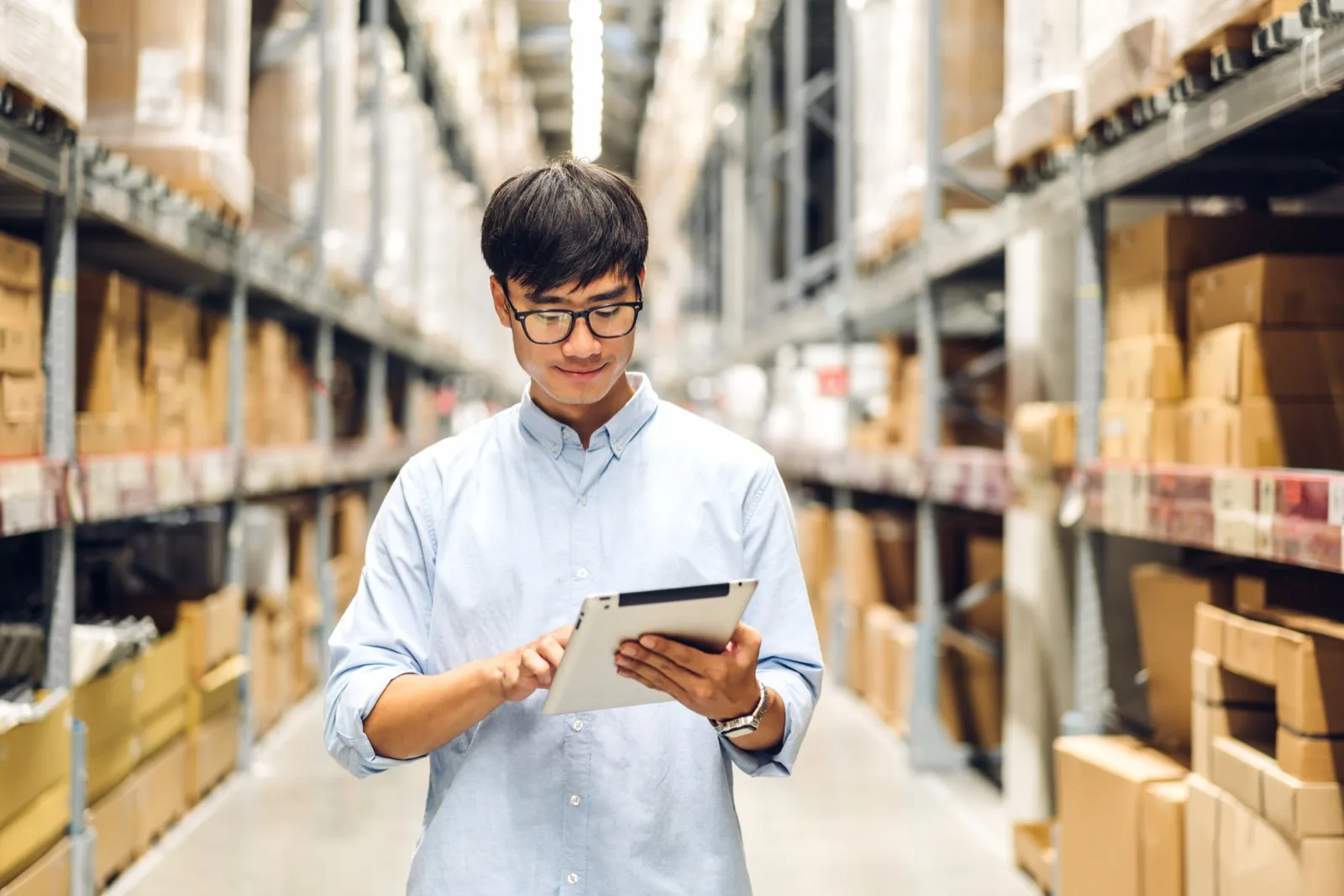 Warehouse staff checking order details on a tablet between stocked shelves