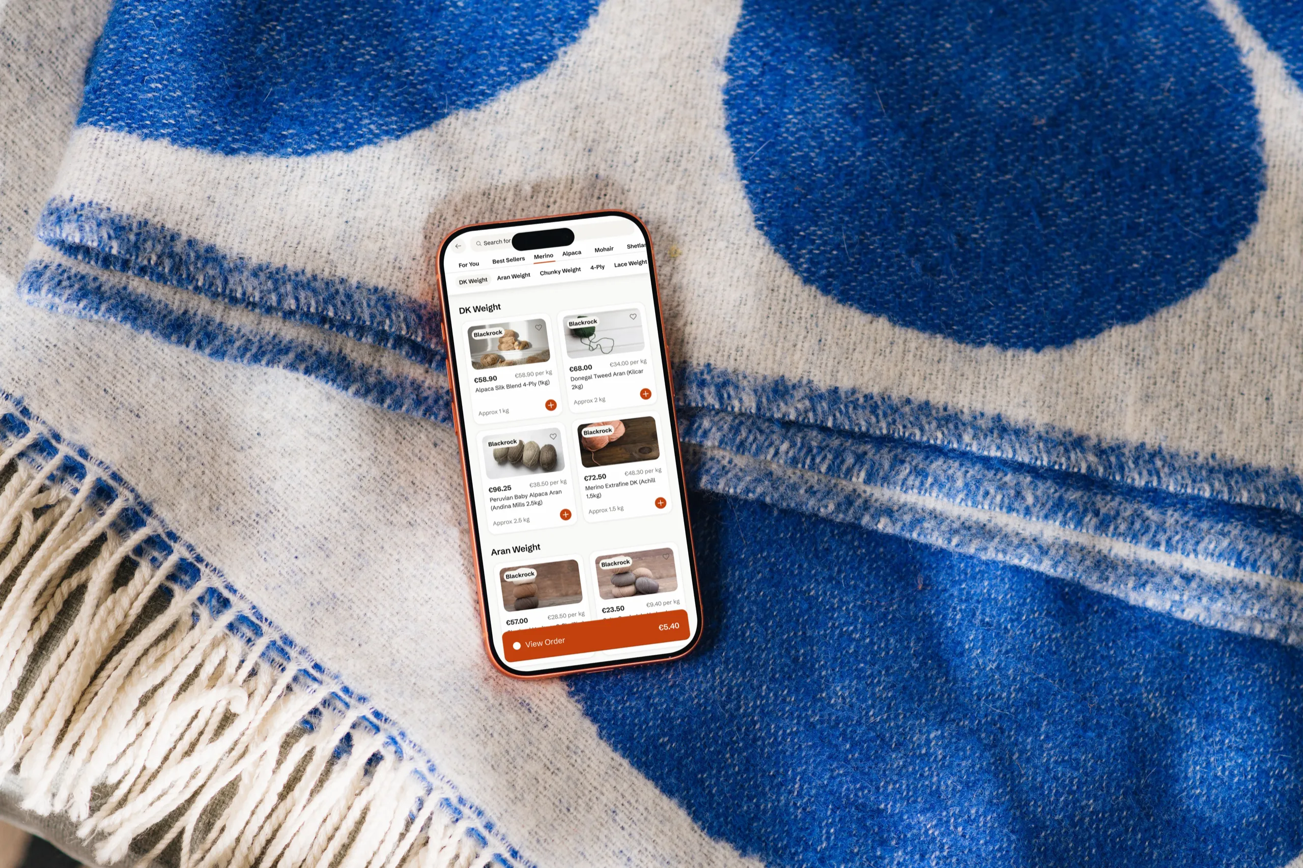 Browsing yarn by weight in the Fathom app, on an iPhone lying on a blue patterned wool blanket
