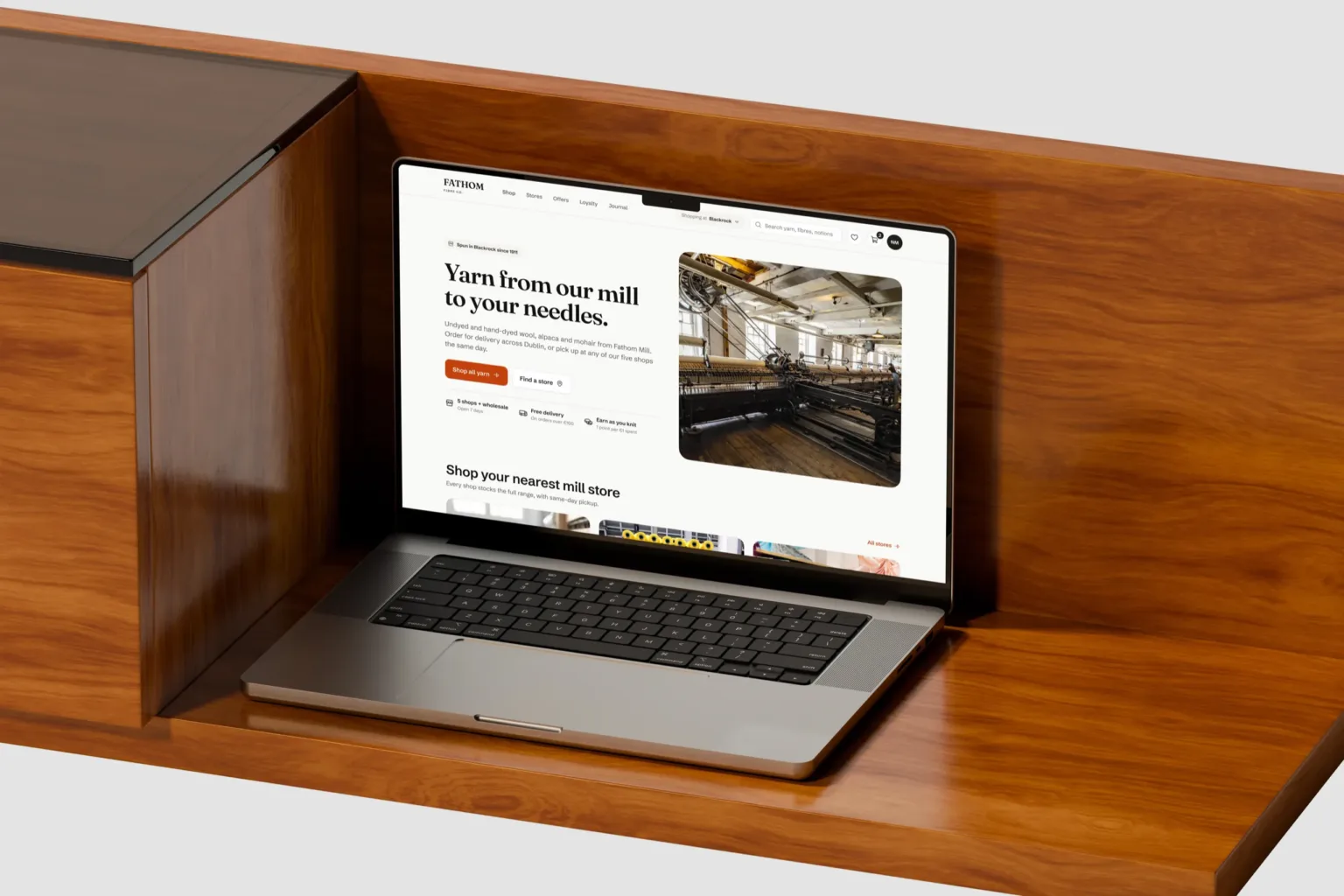 The Fathom web shop homepage on a MacBook Pro on a walnut sideboard