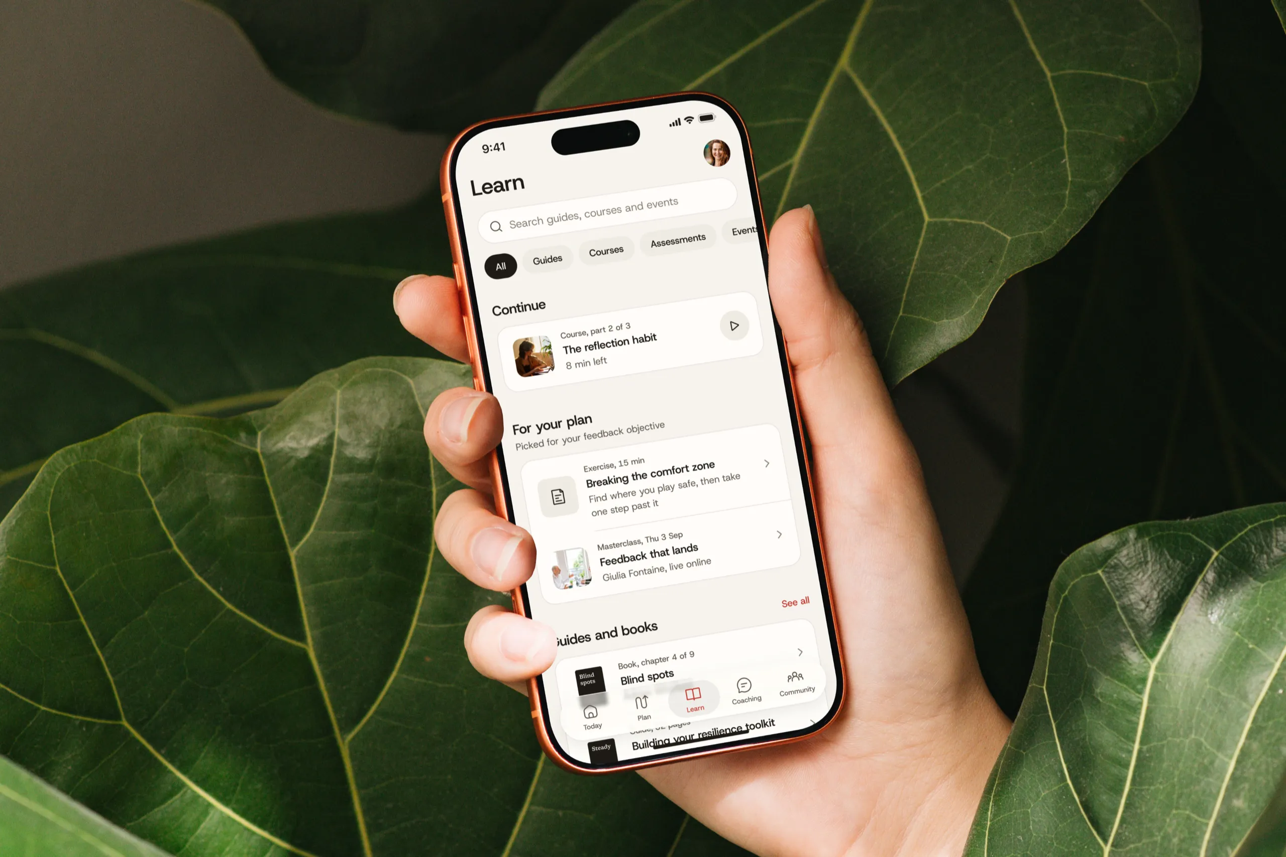 The Throughline Learn screen on an iPhone held in one hand among fig leaves