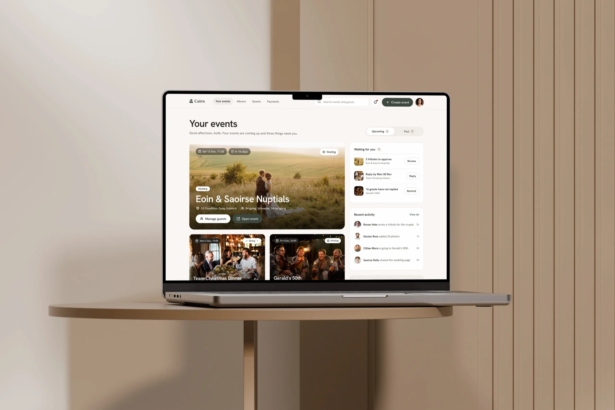 The Cairn web app's Your events page, led by Eoin and Saoirse's wedding, on a MacBook on a round wooden side table