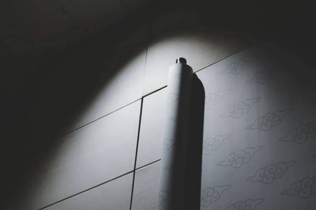 A roll of paper hanging against a tiled wall in a pool of light