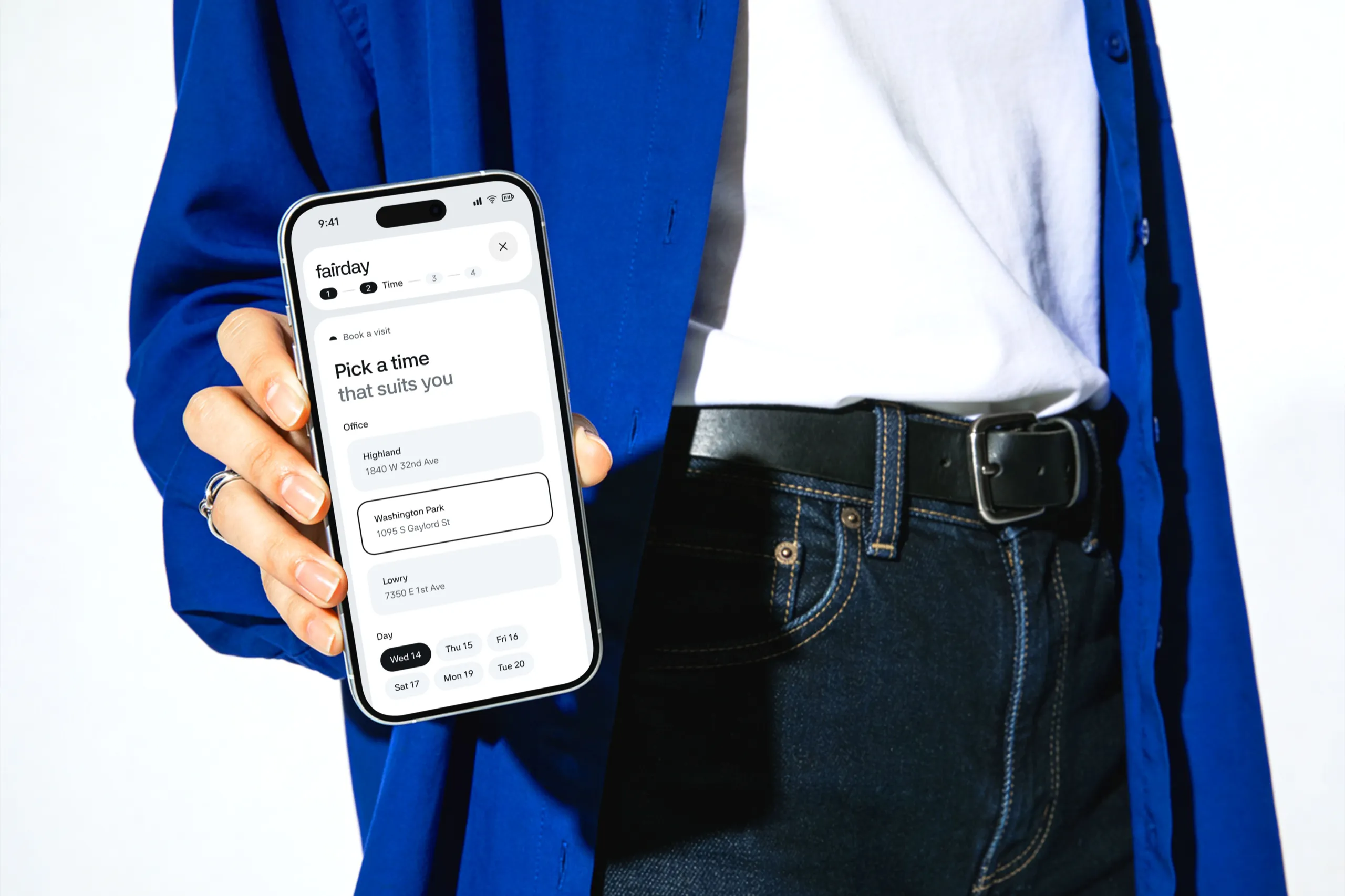 The Fairday booking step Pick a Time That Suits You on an iPhone held against a blue jacket