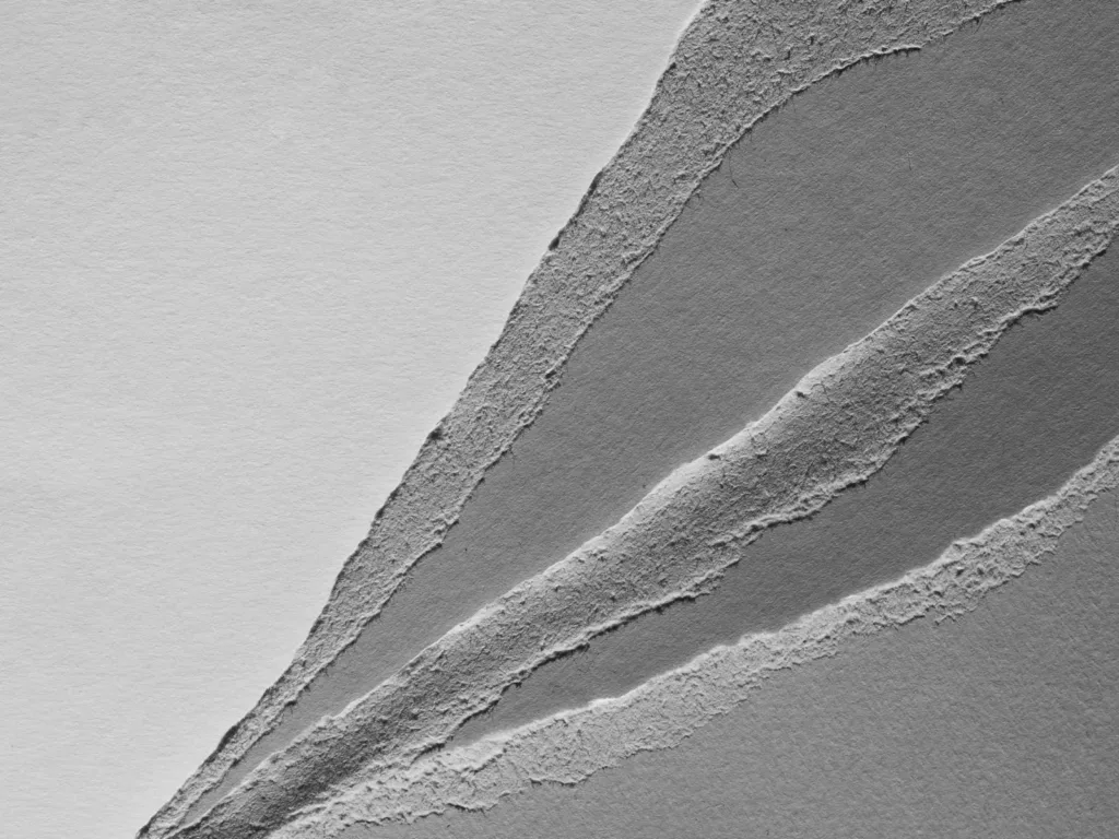Layers of torn grey paper in several tones fanning out from one corner