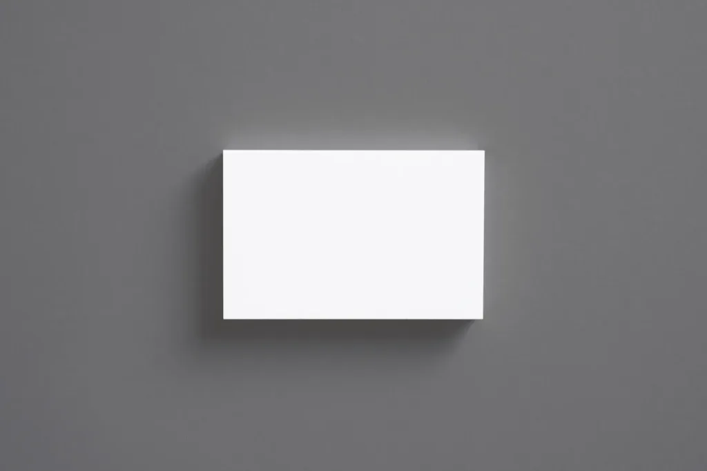 A stack of blank white cards on a mid grey surface