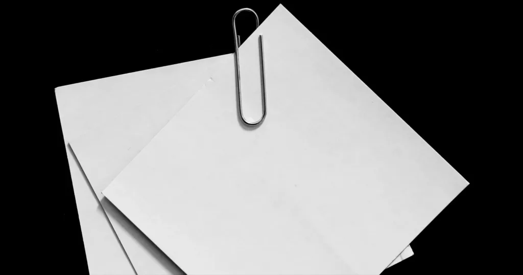 Three white paper notes held together by a paper clip, on black