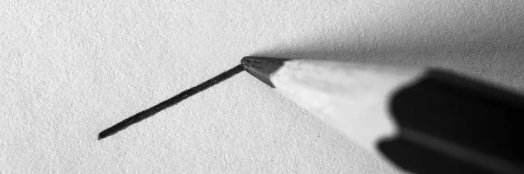 A graphite pencil drawing a straight line on white paper