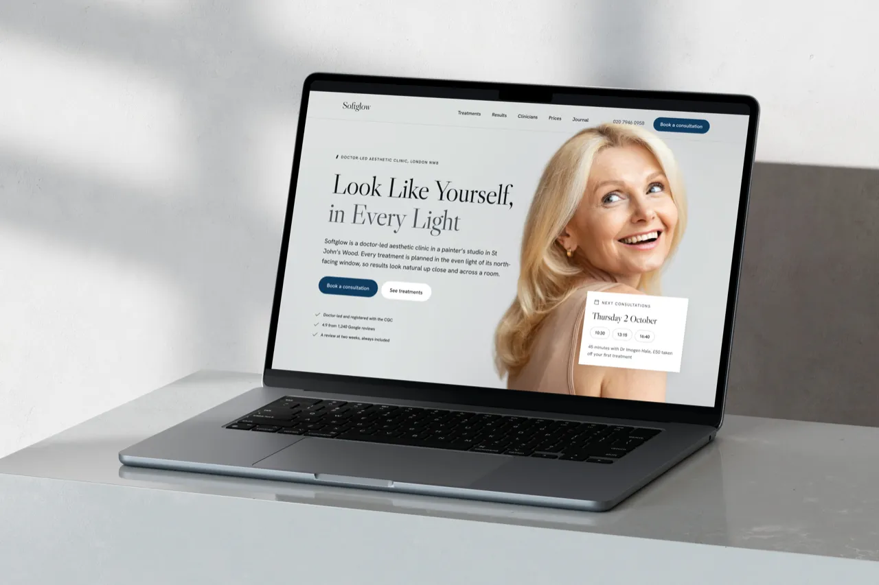 The Softglow homepage, Look Like Yourself in Every Light, on a MacBook Pro on a marble ledge in window light