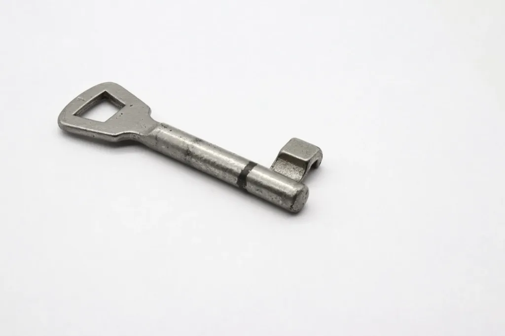 An old metal key lying on a plain white surface