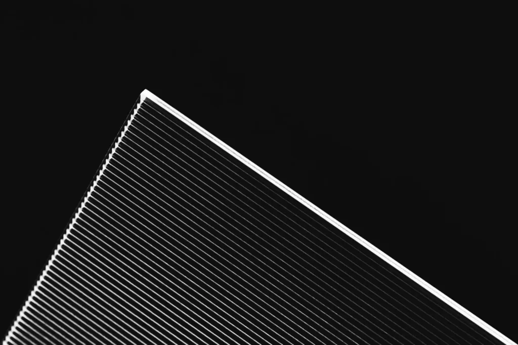 A stack of thin glass sheets seen edge on against black, in black and white